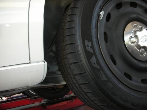 2004 Ford Crown Victoria - Close-up view of a white vehicle's tire and lower body panel, with 'Goodyear' text on the tire sidewall.