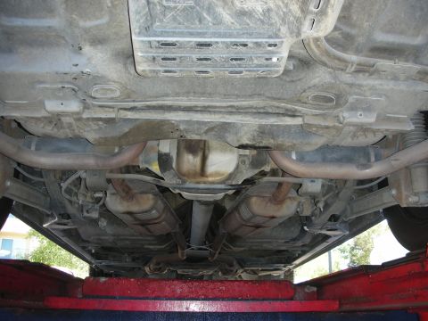 2004 Ford Crown Victoria - The undercarriage of a vehicle is visible, including the exhaust pipes and rear axle assembly.