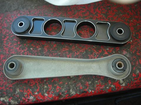 2004 Ford Crown Victoria - Comparison of an aftermarket part and an original suspension component, likely for a vehicle.