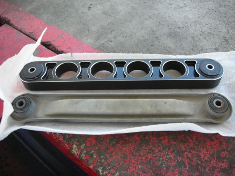 2004 Ford Crown Victoria - Comparison of an aftermarket control arm with a custom design and a stock control arm, likely for a suspension upgrade.