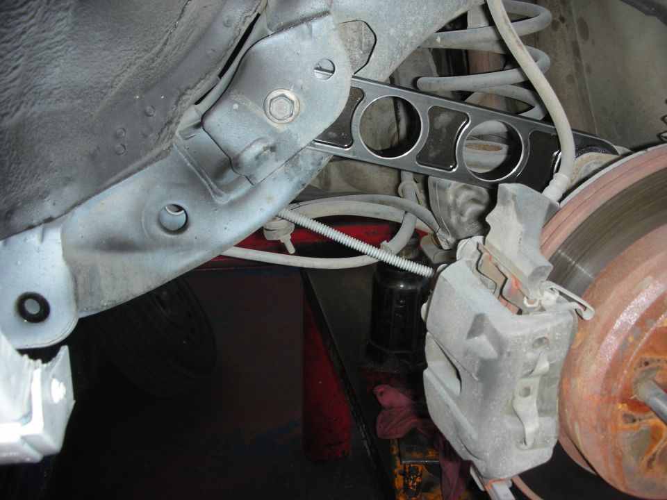 Close-up of a car's rear suspension with a control arm and brake caliper visible