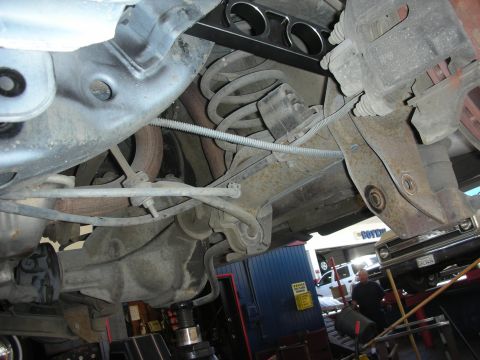 2004 Ford Crown Victoria - Undercarriage view of a 2004 Ford Crown Victoria, with another vehicle partially visible in the background.
