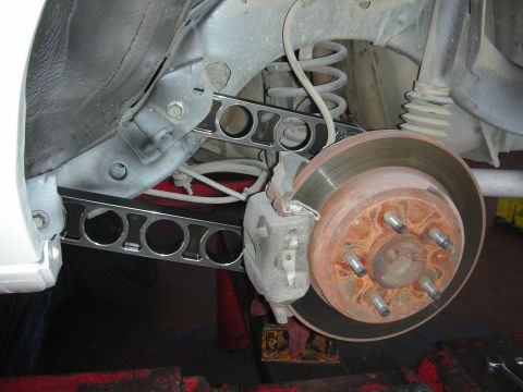 2004 Ford Crown Victoria - Aftermarket rear suspension control arm installed on a vehicle, showing the brake assembly.