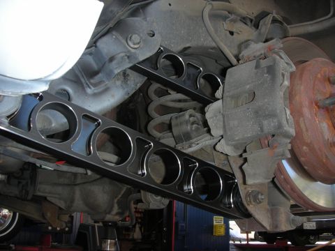 2004 Ford Crown Victoria - Close-up view of custom rear control arms being installed on a vehicle's suspension.
