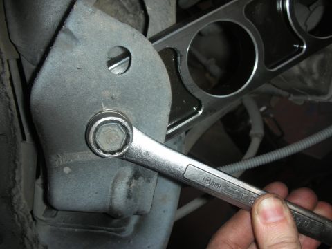2004 Ford Crown Victoria - Close-up of a wrench tightening a bolt on a vehicle's suspension system during a repair.