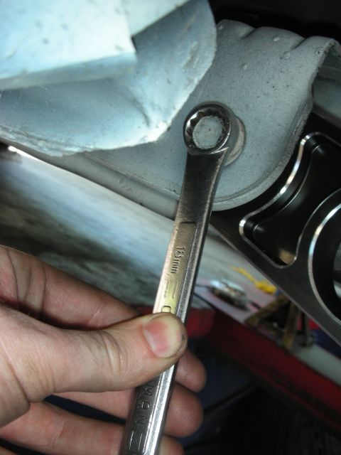 2004 Ford Crown Victoria - A mechanic uses an 18mm wrench to tighten a bolt on a vehicle's suspension system, with an aftermarket part installed.