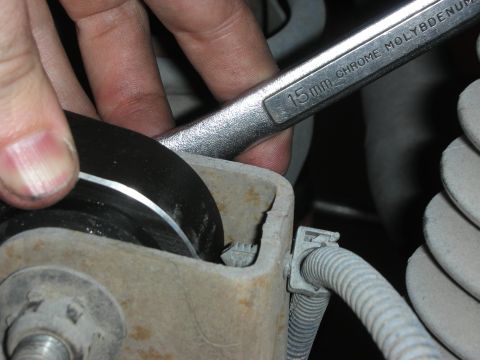 2004 Ford Crown Victoria - A 15mm wrench is used to tighten a bolt on a vehicle's suspension system.