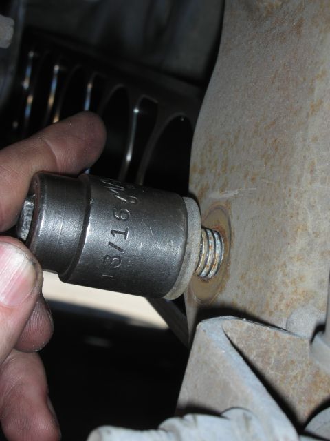 2004 Ford Crown Victoria - A socket wrench is being used to tighten a bolt on a rusty metal component.