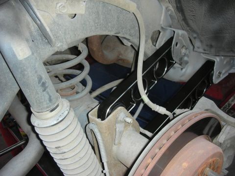 2004 Ford Crown Victoria - Close-up view of a newly installed black rear suspension control arm on a vehicle.
