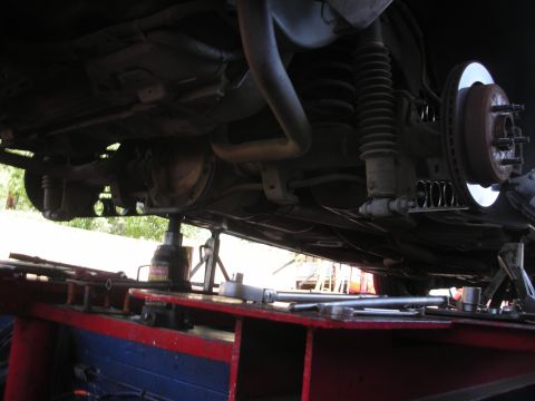 2004 Ford Crown Victoria - Vehicle's rear suspension and axle components are visible while supported by jack stands.