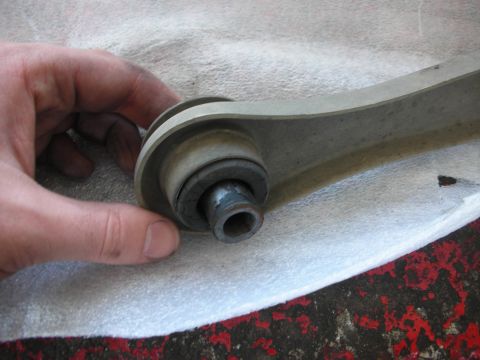 2004 Ford Crown Victoria - A hand inspects a worn control arm bushing, indicating a potential automotive repair issue.