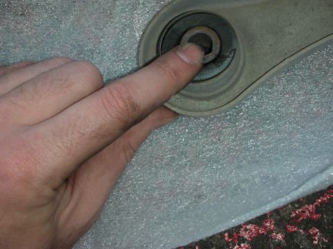 2004 Ford Crown Victoria - Close-up of a hand interacting with a vehicle's control arm bushing.