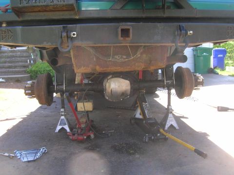 1996 Ford Bronco - The rear of a vehicle is suspended by jack stands, showing the axle and suspension components.