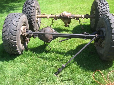 1996 Ford Bronco - Front axle and suspension parts are shown resting on grass.