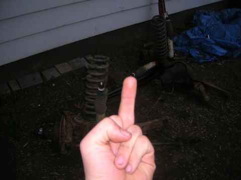 1996 Ford Bronco - Vehicle suspension parts are visible on the ground, with a hand giving the middle finger in the foreground.