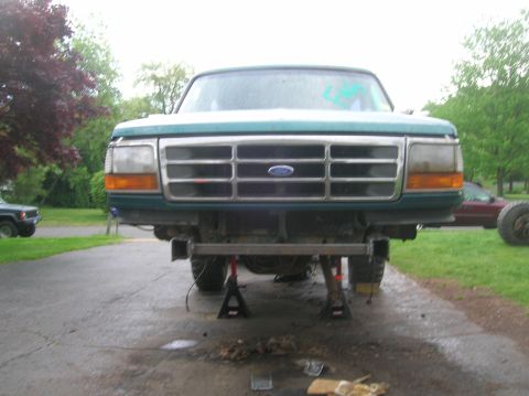 1996 Ford Bronco - A green Ford truck is elevated on jack stands, showing its front grille and headlights.