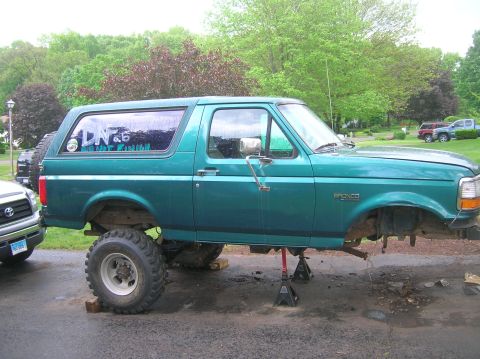 1996 Ford Bronco - A teal 1996 Ford Bronco is shown on jack stands with its front end disassembled.