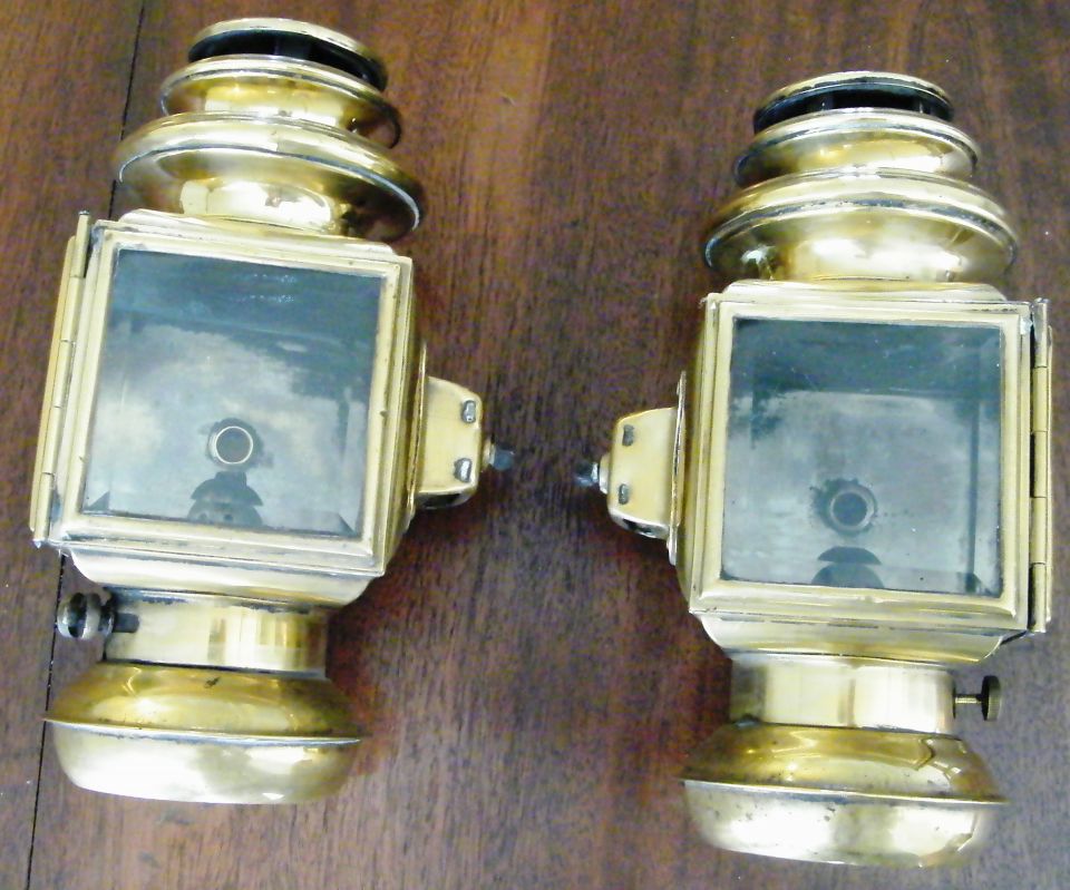 Pair of brass kerosene coach side lamps face-up on wood table with square lenses