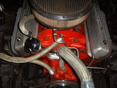 1956 Ford Fairlane - Detailed view of a V8 engine, red block, chrome valve covers, and braided fuel lines.