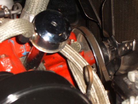 1956 Ford Fairlane - Engine bay details show a chrome cap and a fan belt on a red engine block.