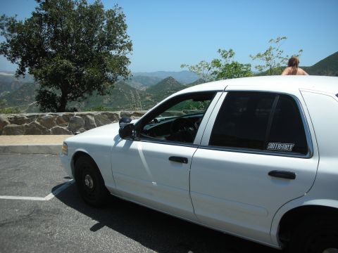 2004 Ford Crown Victoria - Side profile of a white 2004 Ford Crown Victoria parked with a scenic mountain view in the background.