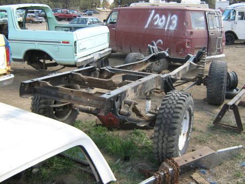 1978 Ford Bronco - A light blue 1978 Ford Bronco body sits next to its chassis in a junkyard, with other vehicles visible.
