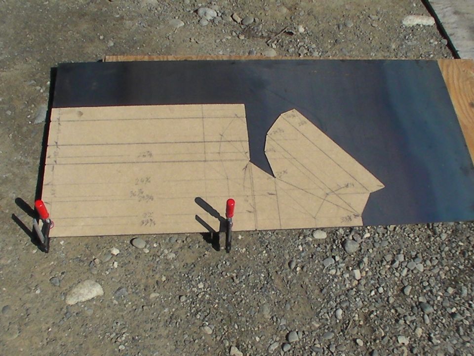 Paper template for a vehicle part on a metal sheet, held by clamps