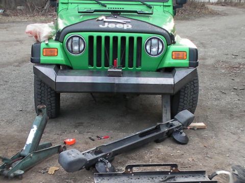 1987 Suzuki Samurai - A green Jeep Wrangler is shown from the front with its bumper removed and lying on the ground.