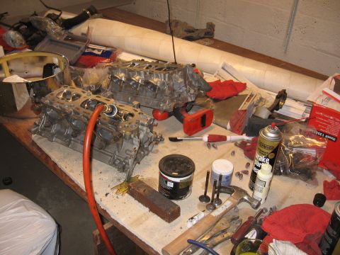 1991 Mitsubishi 3000GT - Engine cylinder heads and parts are laid out on a workbench for repair or maintenance.