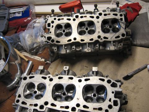 1991 Mitsubishi 3000GT - Engine cylinder heads are shown on a workbench, possibly during a repair or rebuild process.