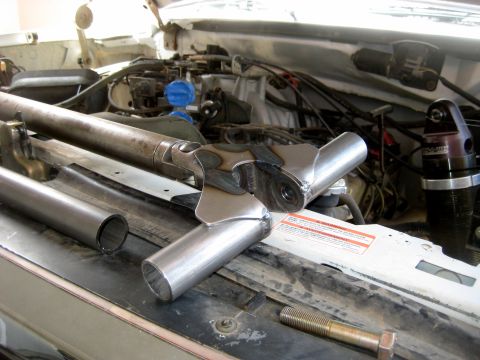 1996 Ford Bronco - Custom suspension parts and a shock absorber are laid out in the engine bay of a vehicle.