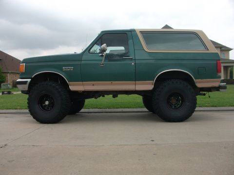 1989 Ford Bronco - This lifted 1989 Ford Bronco is painted green with tan trim and sits on large off-road tires.