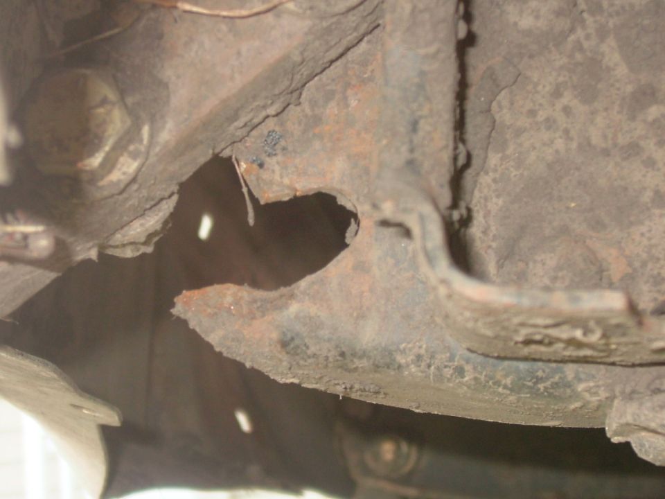 Close-up of heavily rusted metal frame section with a large bolt visible