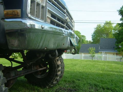 1988 Ford F-150 - Close-up view of the front bumper and off-road tire of a 1988 Ford F-150, with a green license plate attached.