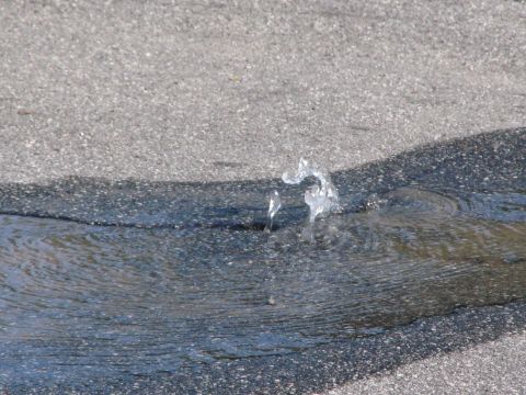 1968 Ford Mustang - A water main break causes water to erupt from the asphalt, creating a puddle and spray.