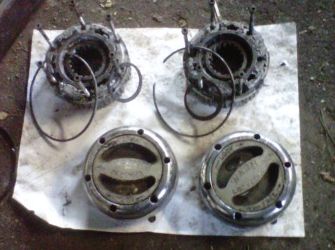 1995 Ford Bronco - A pair of disassembled Warn manual locking hubs laid out on a white board, with the greasy splined internal bodies and snap rings at the to…