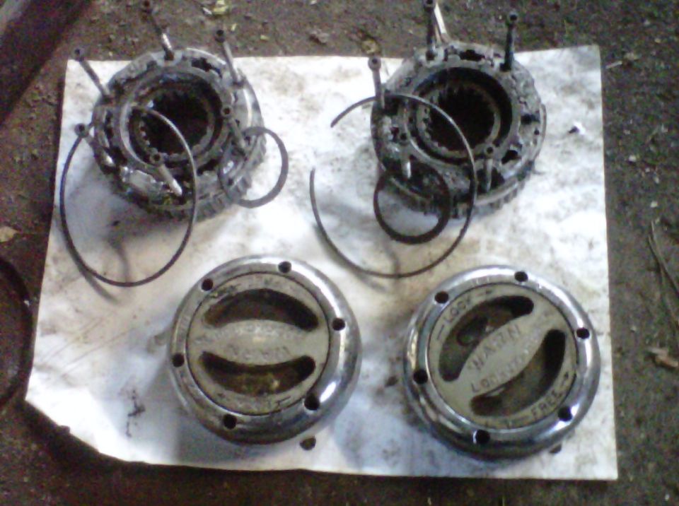 Two disassembled Warn manual locking hubs with LOCK/FREE dial caps and snap rings