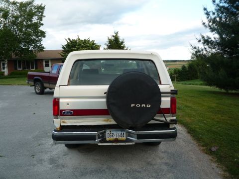1988 Ford Bronco - The rear of a Ford Bronco is shown, with a spare tire mounted on the back and a license plate visible.