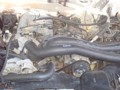 1992 Ford Bronco - Close-up view of a vehicle's engine compartment, showing various mechanical components and hoses.