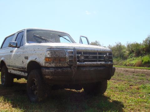 1992 Ford Bronco - This SUV appears to be from the early 1990s, possibly a Ford Bronco, but it's difficult to confirm the exact year due to mud coverage.