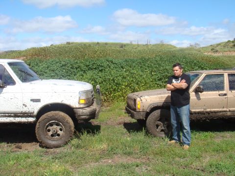1992 Ford Bronco - A white 1992 Ford Bronco and a tan Jeep Cherokee are parked in a muddy field with a man standing by the Jeep.