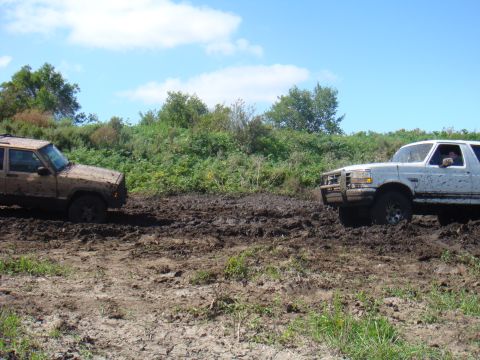 1992 Ford Bronco - Two SUVs navigate a muddy trail, one appearing to be a 1992 Ford Bronco.
