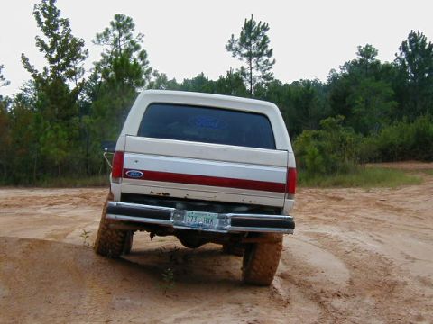 1990 Ford Bronco - This 1990 Ford Bronco is shown from the rear, navigating a muddy, off-road trail.