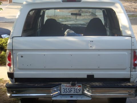 1992 Ford Bronco - Rear view of a white 1992 Ford Bronco, showing its license plate and chrome bumper.