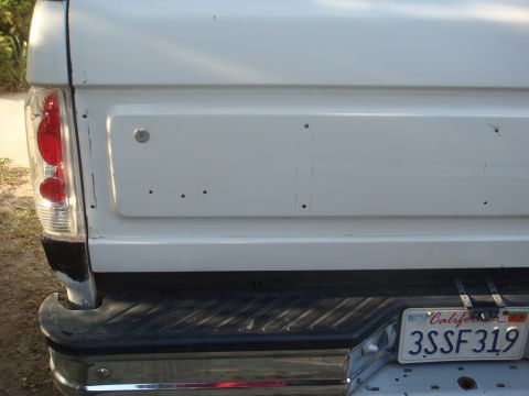 1992 Ford Bronco - Close-up of the rear of a white pickup truck, showing the tailgate and bumper.