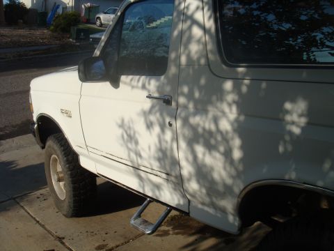 1992 Ford Bronco - A white 1992 Ford Bronco is parked on a concrete driveway, viewed from the side.