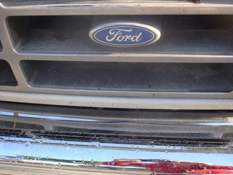 1992 Ford Bronco - Front grille detail of a Ford vehicle, showing the emblem and part of the bumper.