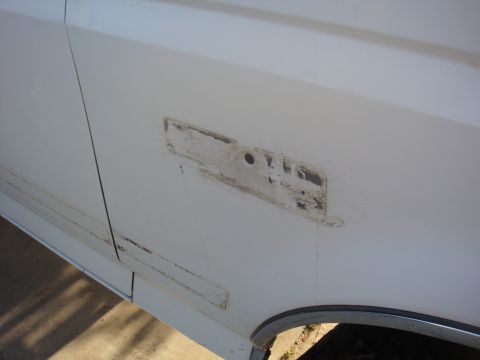 1992 Ford Bronco - Close-up view of a white vehicle's fender showing evidence of removed trim and damaged paint.
