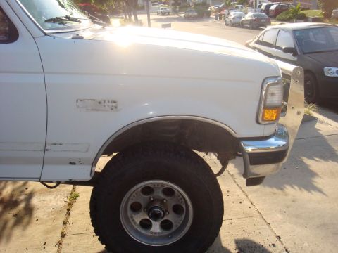 1992 Ford Bronco - Front view of a white 1992 Ford Bronco, showing the fender, wheel, and bumper detail.