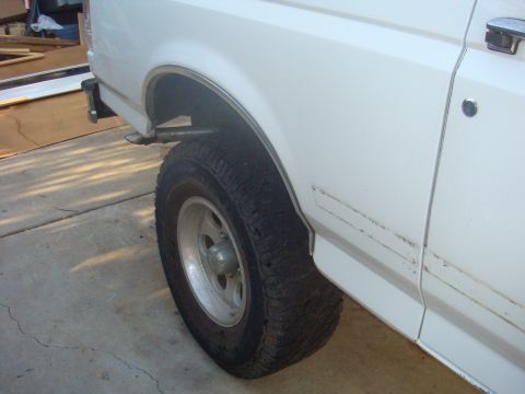 1992 Ford Bronco - Close-up view of the rear wheel and fender of a white 1992 Ford Bronco.